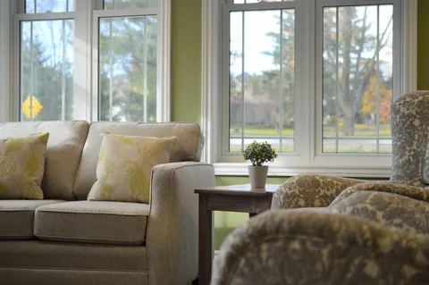 Sofa and patterned armchairs beside windows overlooking trees