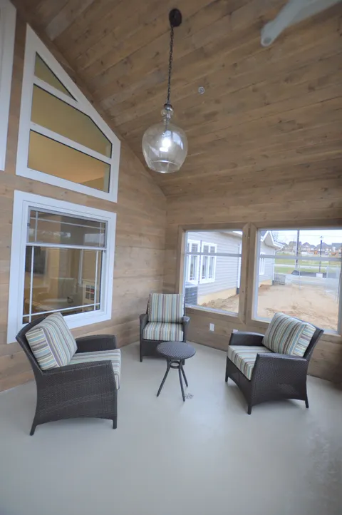Enclosed porch with wicker chairs, windows and a timber ceiling