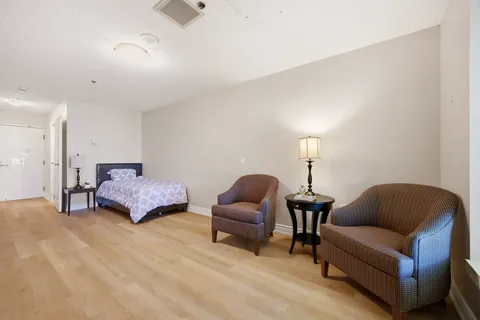 Suite with a single bed, two patterned armchairs, side tables and lamps.