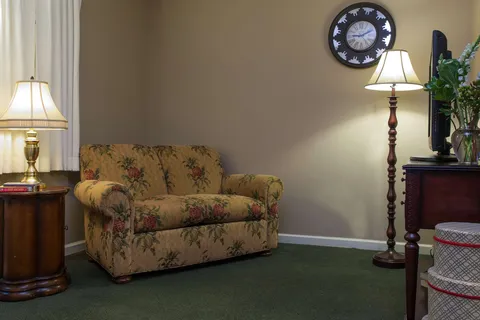 Sitting area with a floral armchair, lamps and a wall clock