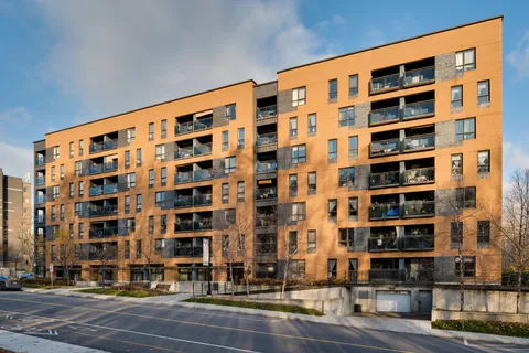 Brick residence with balconies facing a paved parking area