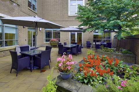 Garden patio with tables, chairs, umbrellas and flowering plants.