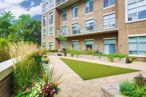 Outdoor putting green beside the residence and planted beds.