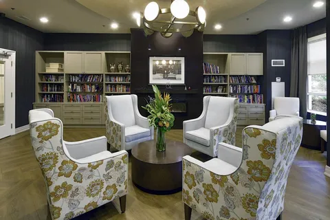 Library with bookcases, upholstered chairs and a round table.