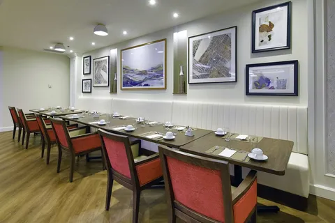 Private dining room with a long set table and framed artwork.
