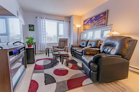 Sitting area with black leather seating, a patterned rug and windows