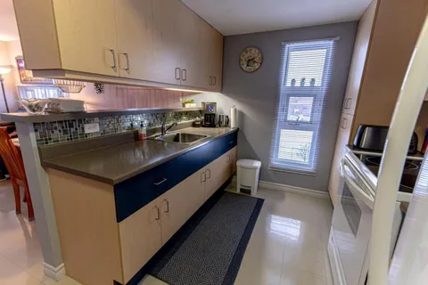 Kitchen with light wood cabinets, a sink and a tiled backsplash