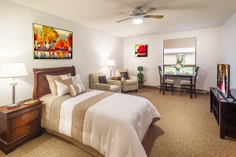 Bedroom with a bed, armchairs, a table and landscape pictures