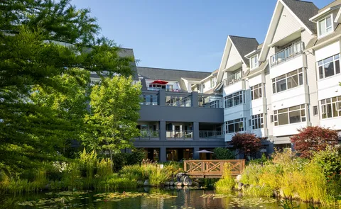 Residence wings overlook a pond, gardens and a small footbridge.