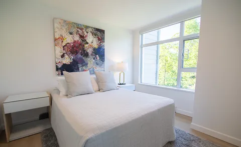 Bedroom with a double bed, bedside tables and large windows.