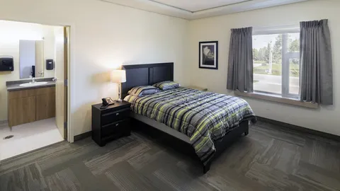 Bedroom with a double bed, bedside lamp, window and an adjoining bathroom.