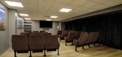 Cinema room with upholstered chairs and a wall-mounted screen