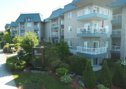 Multi-storey residence with balconies, a sign and landscaped entrance