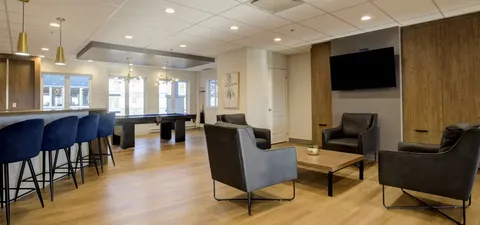 Sitting area with grey chairs beside a counter and wall-mounted television