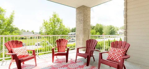 Covered balcony with red chairs overlooking trees
