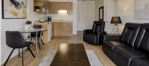 Room with black seating, a dining table and kitchenette