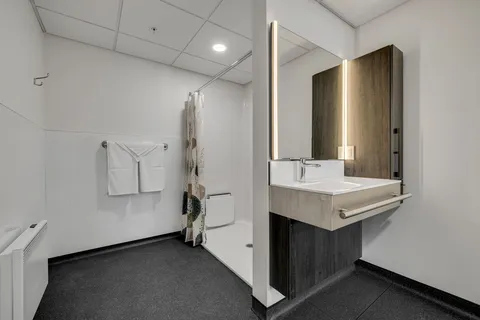 Bathroom with a vanity, illuminated mirror and accessible shower