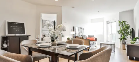Apartment dining area with a set table, upholstered chairs and plants