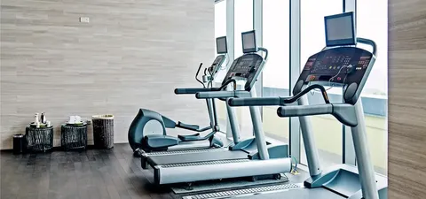 Treadmills beside windows and baskets of towels