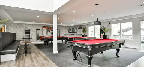 Billiards room with red tables, cue racks and a long padded bench