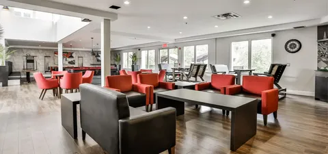 Room with red and dark chairs around tables beside tall windows