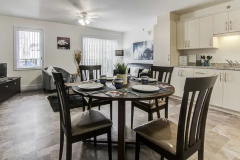 Suite dining and living area beside a white kitchen.