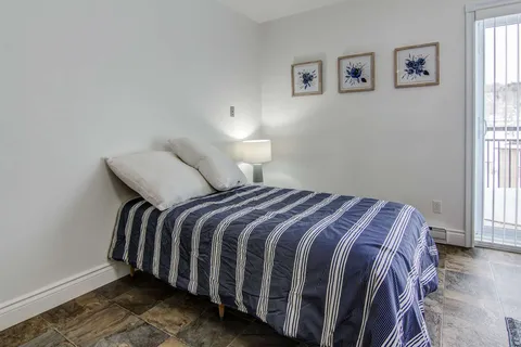 Bedroom with a striped bedcover beside a patio door.