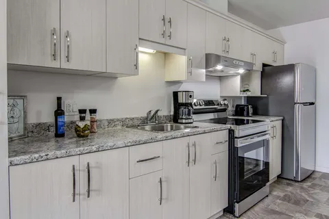 Kitchen with white cupboards, a stove and refrigerator.