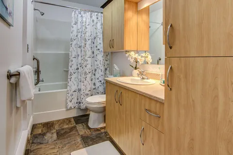 Bathroom with wooden cupboards, a vanity and bathtub.