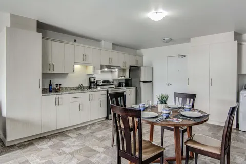 Suite kitchen with white cupboards and a round dining table.