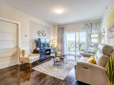 Sitting area with reclining armchairs, a television, coffee tables and glass doors to a balcony