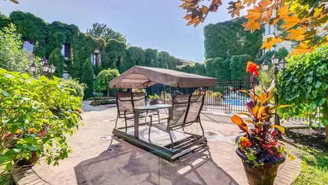 Courtyard with covered patio seating, flower planters, an outdoor pool and ivy-covered building walls