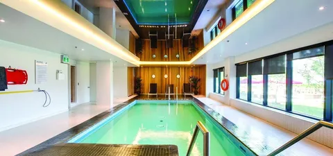 Indoor swimming pool with a handrail and tall windows