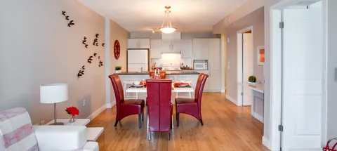 Open sitting and dining area beside a white kitchen