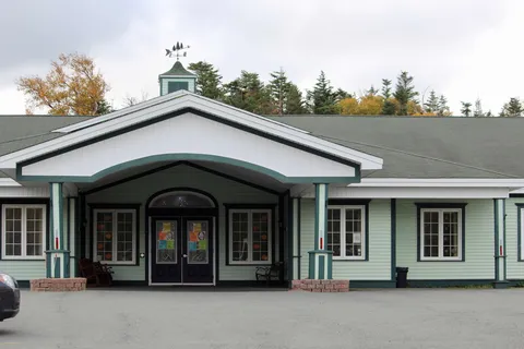 Single-storey residence with a covered entrance, green trim and cupola.