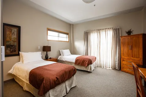 Two beds beside a bedside table, wardrobe and curtained window