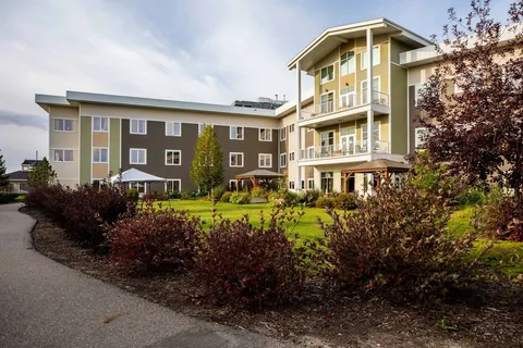 Multi-storey building beside a lawn, shrubs and a paved path