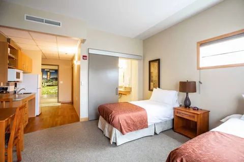 Twin beds beside a kitchenette and an open bathroom doorway