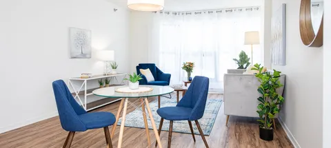 Living area with blue chairs, a glass table and a bright window