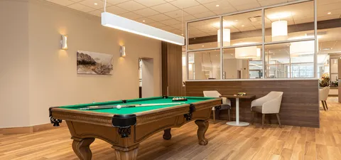 Billiard table beside chairs and a glass partition