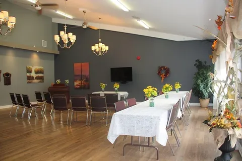 Room with a long table, chairs and a television