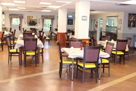 Dining room with round tables and chairs beneath ceiling lights.