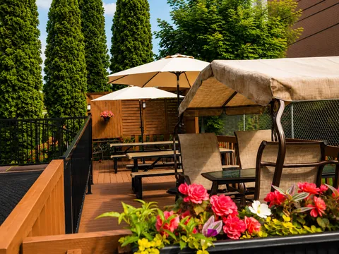 Wooden patio with outdoor chairs, parasols, a canopy and colourful flowers