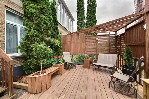 Wooden deck with outdoor chairs, benches, planters and tall shrubs