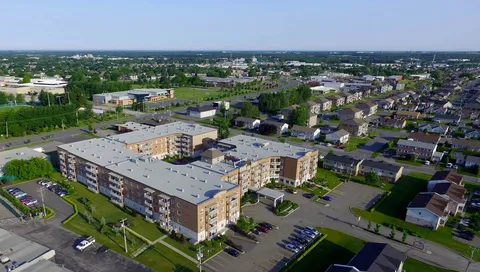 Aerial view of a large brick residential building with balconies, lawns and parking areas