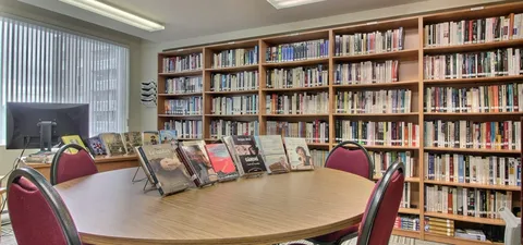 Library shelves beside a round table and reading area.