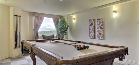 Billiards table beside windows and a wall clock.