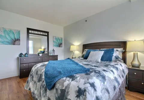 Bedroom with a bed, dresser, lamps and wall artwork.