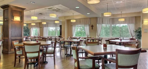 Dining room with tables and chairs beside large windows.