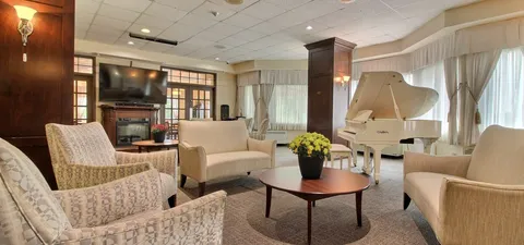 Lounge with sofas, armchairs and a white grand piano.